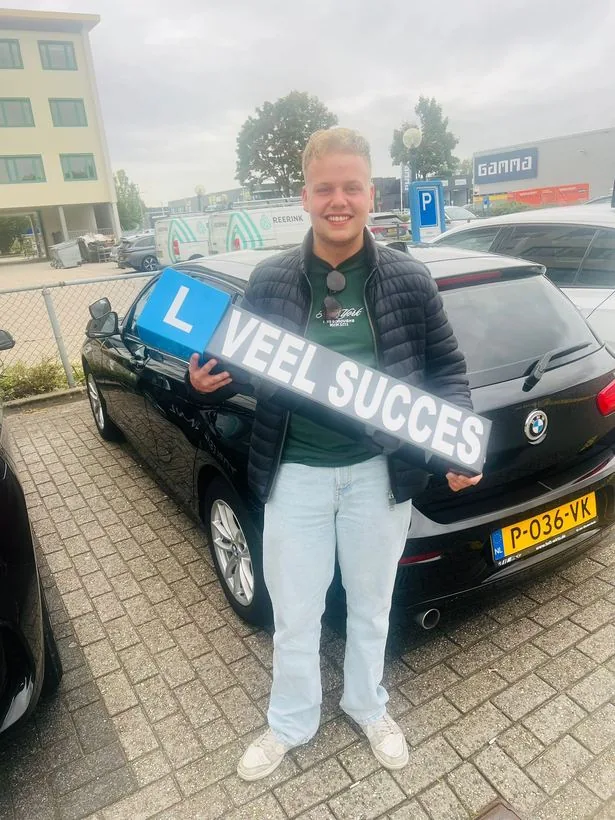 Geslaagde leerling met VEEL SUCCES-bord bij de lesauto